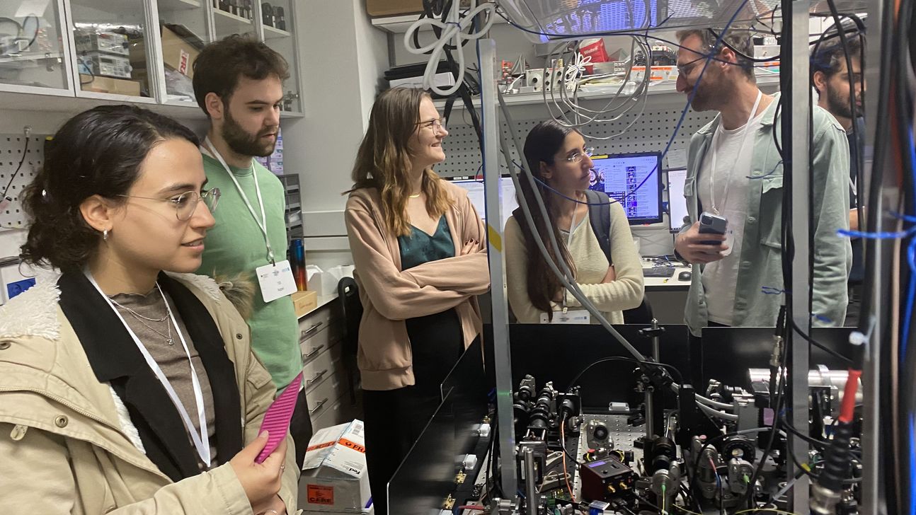 Studierende besuchen ein Quantenlabor. Sie stehen an einem Tisch mit Messgeräten.