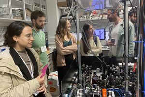 Students visiting a quantum lab. They stand at a table with measuring devices.