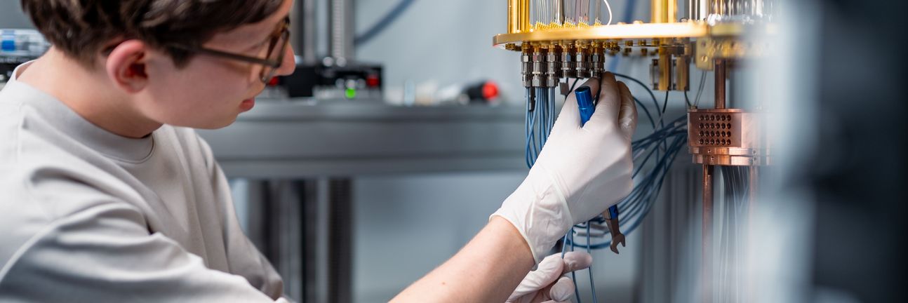Ein Wissenschaftler montiert Kabel an einem offenen Kryostaten für supraleitendes Quantencomputing.