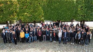 The participants of the MQV review meeting standing in a group infront of trees.