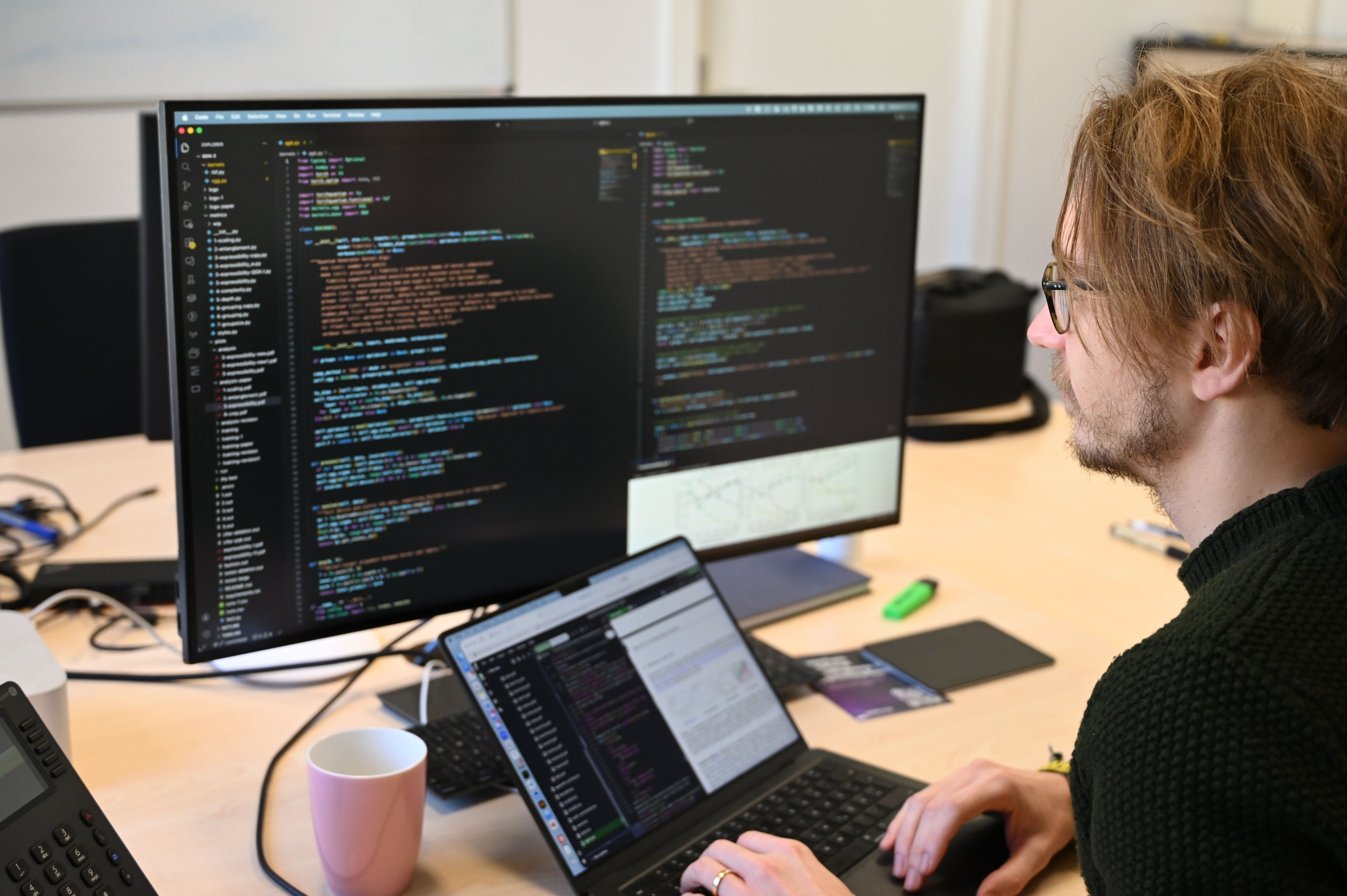 Philipp Altmann in front of laptop and screen showing programming code.