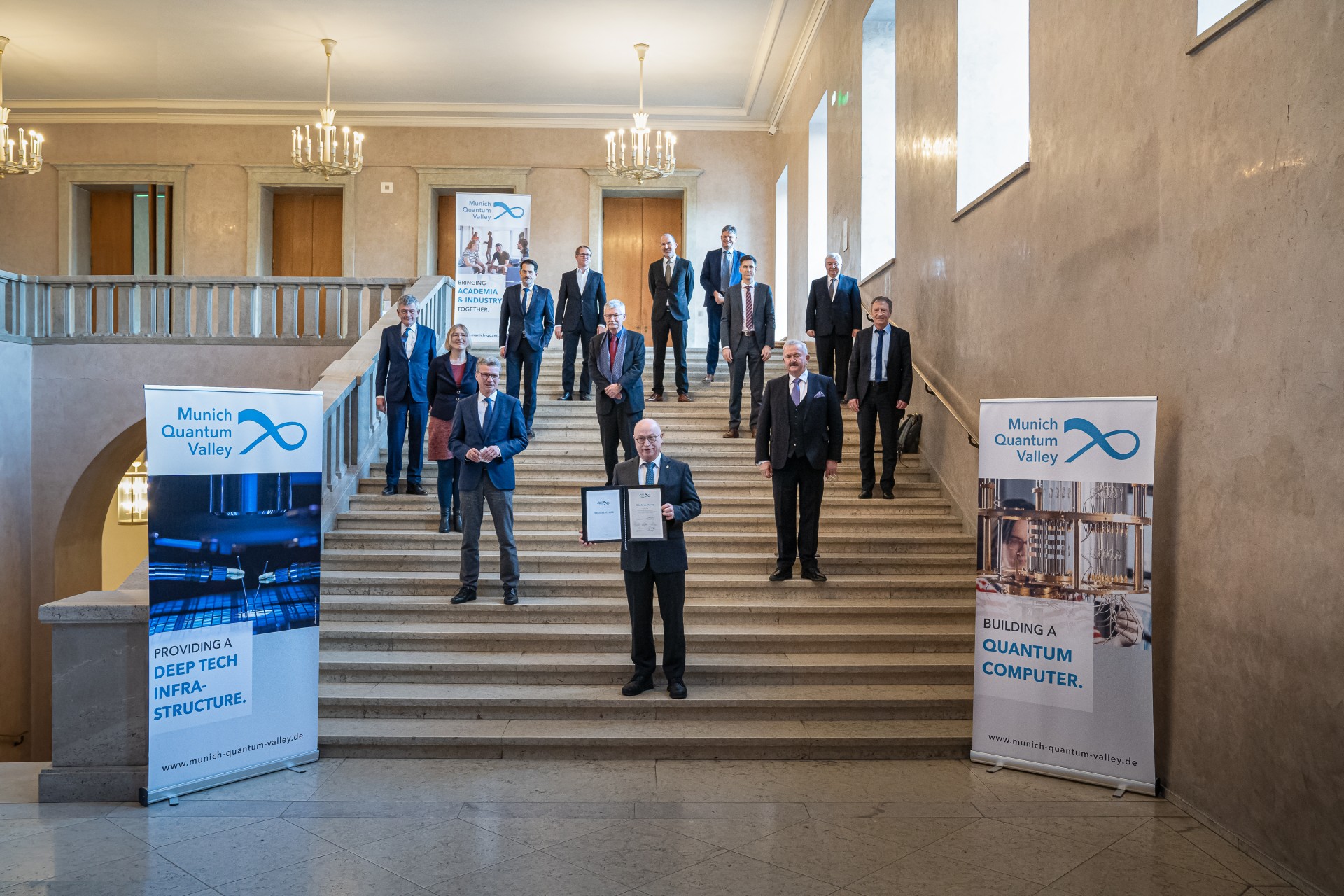 The presidents of the organizations involved in the Munich Quantum Valley association stand on a staircase. Martin Stratmann holds the founding document.